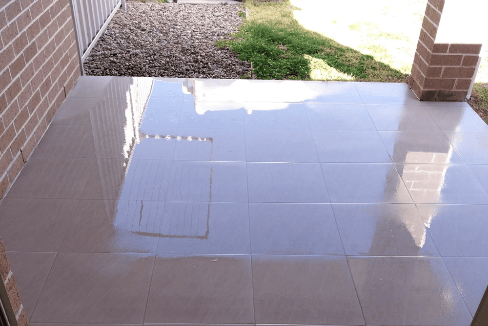 Cleaned, glossy outdoor patio tiles on a verandah reflecting the surrounding light-